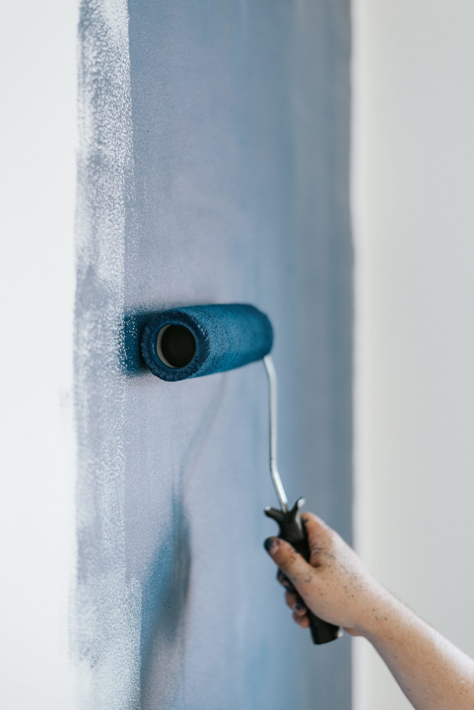 A closeup shot of a female using paint rollers with the color blue